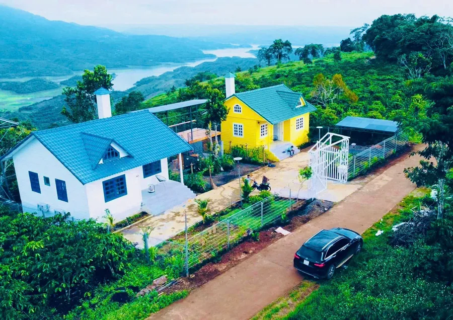 Nhìn từ trên cao: đường đất đỏ, vườn cây, nhà lưới nhỏ trên đồi bên hồ Tà Đùng